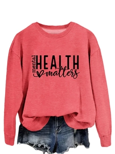 Detail of coral pink mental health matters slogan sweatshirt paired with denim shorts