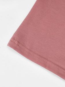 Macro-opname van de dubbelgestikte zoom van een gebreid T-shirt met V-hals in oudroze