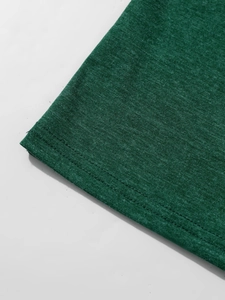 Detailopname van de dubbele naaldstiksels op de zoom van het donkergroene gebreide t-shirt