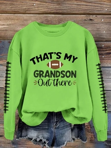 Détail d'un sweat-shirt vert avec imprimé football That's My Grandson sur fond en bois