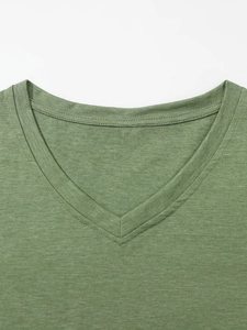 Detail van grasgroen T-shirt met V-hals met fijne gebreide textuur en nette stiksels
