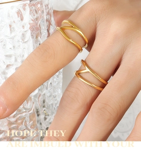 Detailed close-up of a golden double-layered wavy ring on a model hand with glass