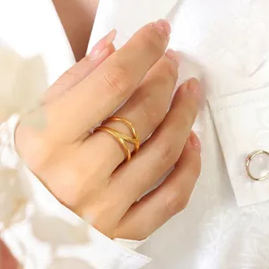 Minimalist double-layer cross ring in polished 18k gold plating on model's finger