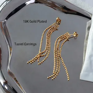 Elegant 18K gold plated tassel drop earrings with metal bead chains on a silver tray