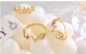 Gros plan d'une bague LOVE couronne dorée avec zircon sur fond de perles blanches