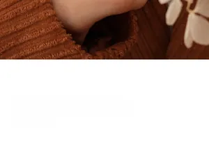 Détail du tissu en velours côtelé marron avec texture à fines rayures et bord de manche