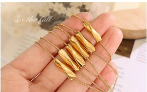 Detailansicht einer goldenen Schlangenkette mit sechs minimalistischen, gedrehten Anhängern
