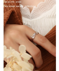 Gros plan d'une bague LOVE en argent avec oxyde de zirconium sur fond de dentelle