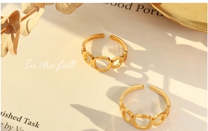 Close-up of two geometric hollow square open rings in gold finish on autumn book background