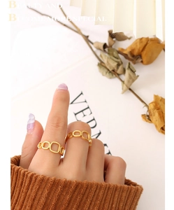 Detail view of stacked gold geometric hollow rings worn on fingers with a warm aesthetic