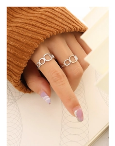 Detail view of silver hollow square geometric rings worn against orange knit fabric