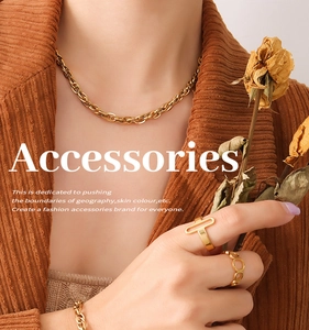 Détail d'un collier à grosse chaîne dorée et de bagues géométriques sur velours