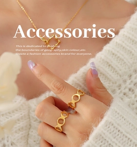 Détail de bagues évidées dorées 18k et collier à pendentif carré sur maille blanche