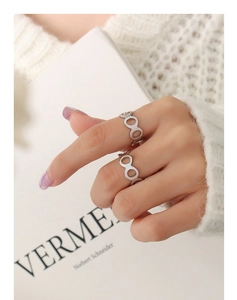 Détail d'une bague géométrique argentée au doigt avec un pull blanc confortable