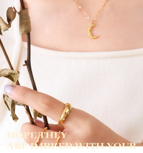 Detail of 18K gold crescent moon pendant necklace and textured rings on model