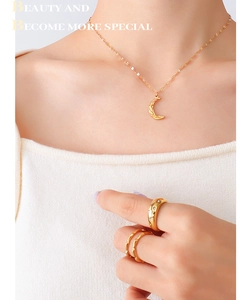 Close-up of 18K gold crescent necklace and matching rings on model for a chic look