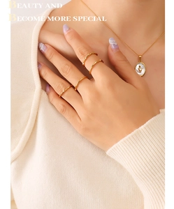 Close-up of a model wearing a gold chain necklace and bamboo-style stacking rings