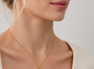Dettaglio ravvicinato della collana a catena fine dorata minimalista indossata dal modello