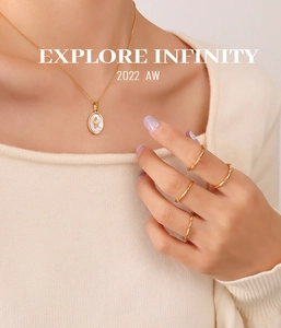 Close-up of 18K gold plated chain necklace with oval shell pendant and geometric rings