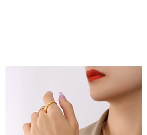 Gros plan du collier portrait doré et des bagues minimalistes portés par un mannequin