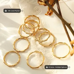 Minimalist 18K gold-plated bamboo-style link rings arranged on an elegant lace background