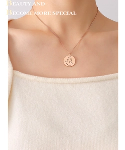Détail du collier avec pendentif portrait en or rose sur mannequin en pull en maille