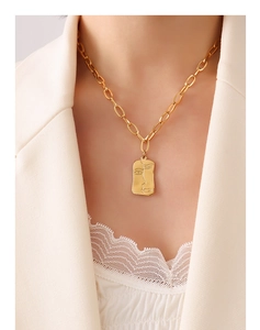 Détail du collier pendentif portrait doré avec visage abstrait sur chaîne trombone