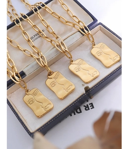 Vue détaillée de pendentifs visage abstrait dorés dans un écrin de bijoux vintage