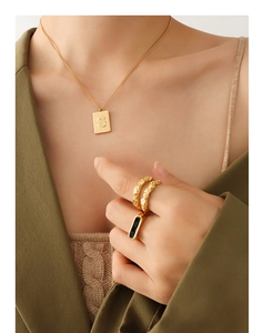 Detail of 18K gold plated S-letter pendant necklace and rings on olive blazer model