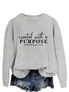 Close-up of Bible verse print on gray crewneck sweatshirt with distressed denim shorts