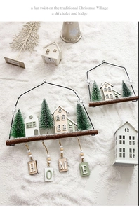 Detalle de casas de madera navideñas para colgar con letras HOME y decoraciones de nieve