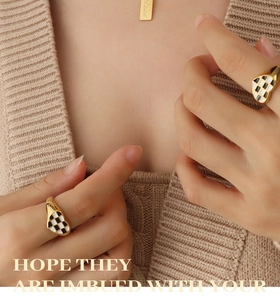 Close-up of heart-shaped checkerboard enamel rings and gold love pendant necklace