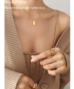 Detail of 18K gold plated snake chain with Love pendant and checkerboard heart rings