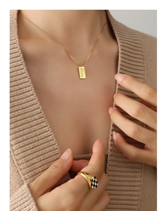 Detail of 18K gold-plated necklace with Love pendant and checkerboard ring on model