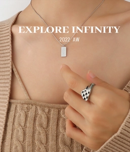 Close-up of engraved Love rectangular pendant and checkered heart ring on sweater