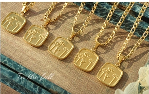 Détail de colliers avec pendentifs carrés fleur en plaqué or 18K sur fond rétro