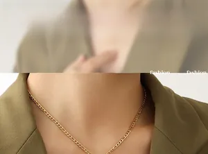 Gros plan d'un collier chaîne Figaro doré porté sur un blazer vert olive élégant