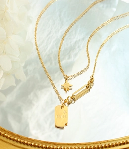 Vue détaillée du collier double rang doré avec pendentifs étoile et BLISS gravé