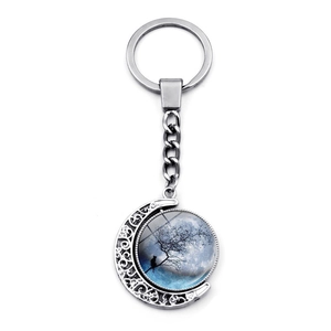 Close-up of rotating moon keychain with a silhouette cat on tree branch design