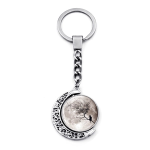 Detailed close-up of a rotatable moon keychain featuring a black cat on a tree branch