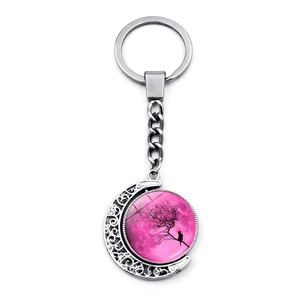 Detail of rotating moon pendant featuring a black cat and tree silhouette on a pink background