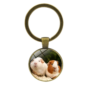 Close-up of a bronze glass keychain featuring two cute guinea pigs on a white background