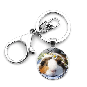 Detail eines silbernen Meerschweinchen-Schlüsselanhängers mit Hamster- und Gänseblümchen