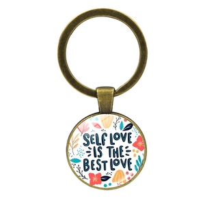 Dettaglio di un portachiavi in bronzo con citazione floreale 'SELF LOVE IS THE BEST LOVE'
