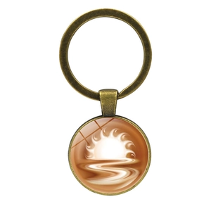 Detail of vintage bronze keychain featuring an abstract sun and wave glass pendant