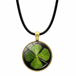 Détail d'un pendentif trèfle en bronze avec pierre de verre sur cordon en cire noire