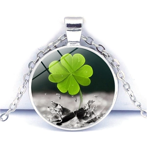 Macro view of a silver four-leaf clover crystal glass pendant necklace with a green motif