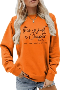 Detail of black text print on an orange crewneck sweatshirt with ribbed cuffs and hem