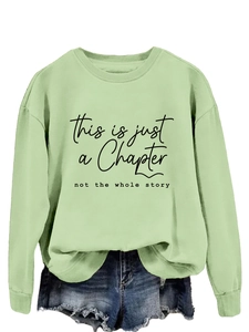 Detail showing the light green sweatshirt with slogan print and denim shorts outfit