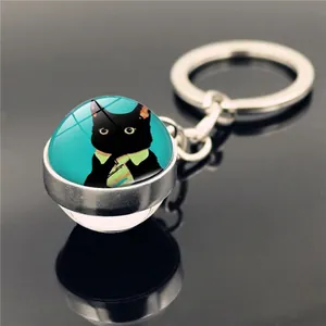 Close-up of a glass dome keychain with an anthropomorphic black cat in a green shirt